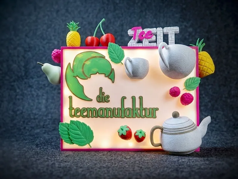Beleuchtete Logo-Box einer Teemanufaktur mit plastischen Früchten und Teekanne